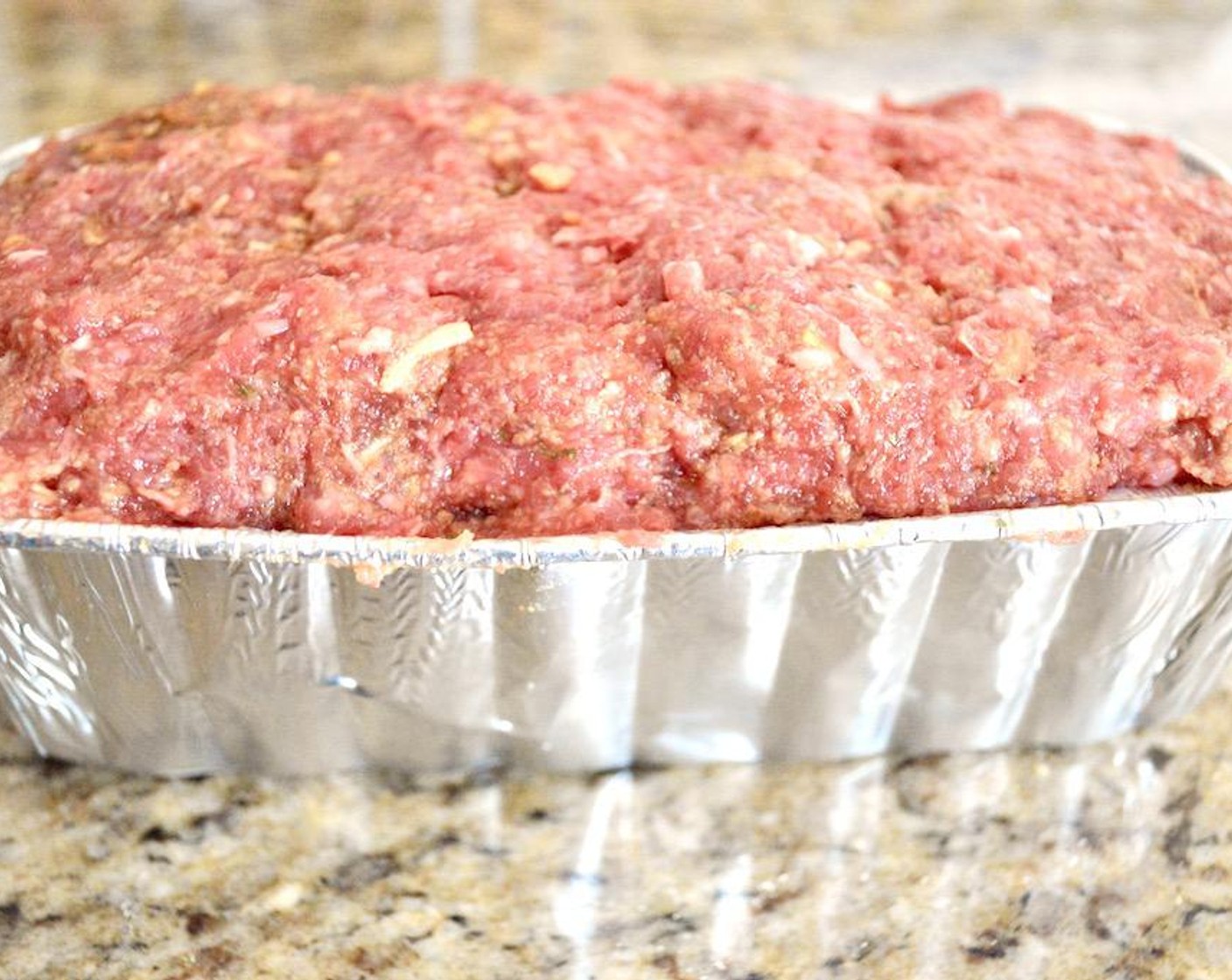 step 2 Get a loaf pan, and combine the Ground Beef (2 lb), Seasoned Breadcrumbs (2/3 cup), Onion Soup and Dip Mix (1 packet), Eggland's Best Classic Eggs (2), Simply Organic Garlic Powder (1 pinch), Salt (1 pinch), and Freshly Ground Black Pepper (1 pinch) in a bowl and use your clean hands to thoroughly mix it together. Press the mixture firmly into the loaf pan and put the full loaf pan on the sheet tray.